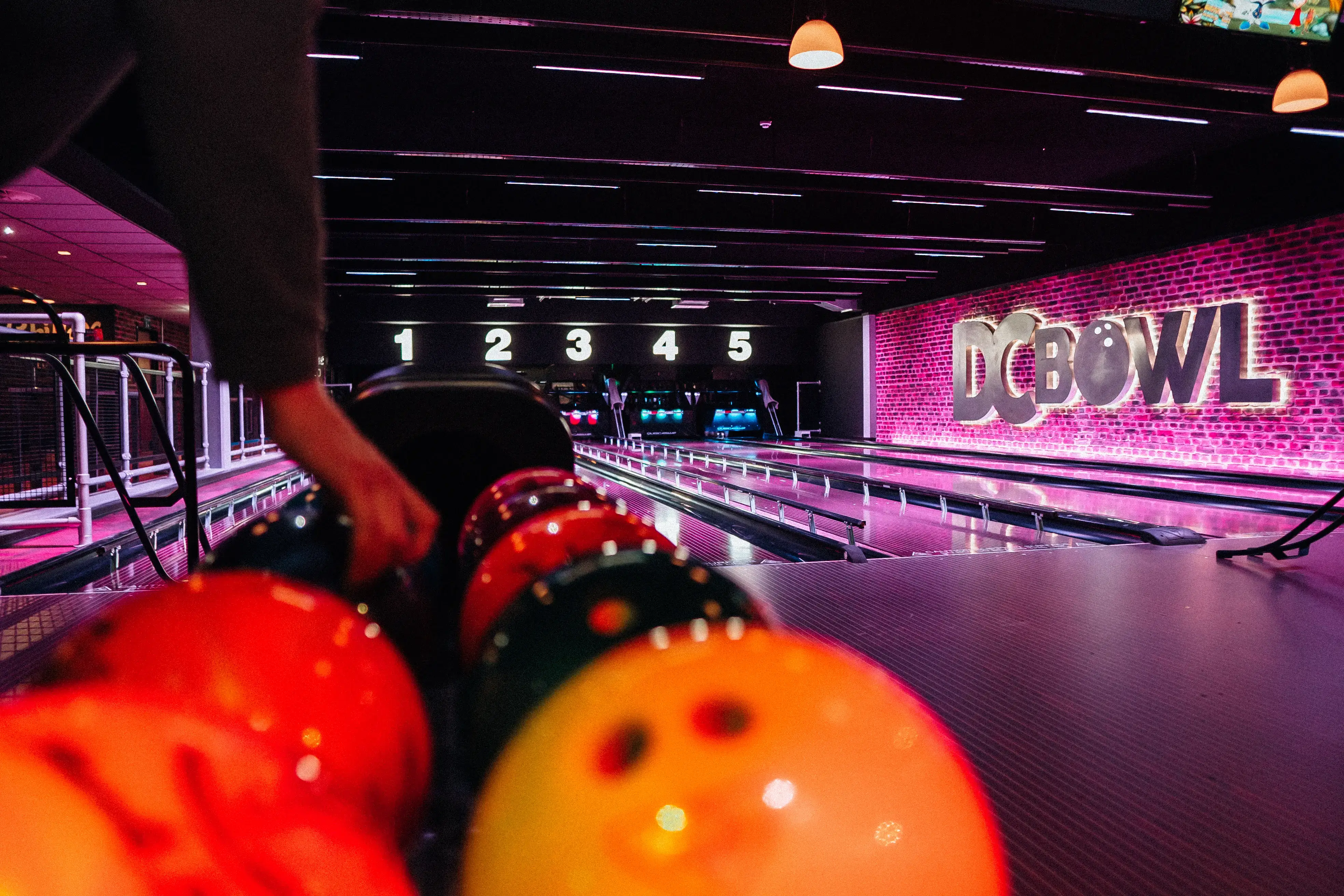 Close up shot of someone picking up a bowling ball from the rack